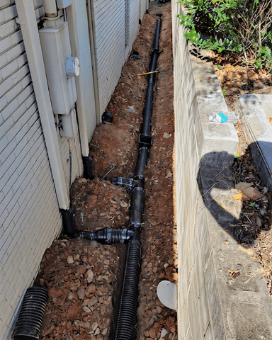 Corrugated drainage pipe routed alongside a house foundation